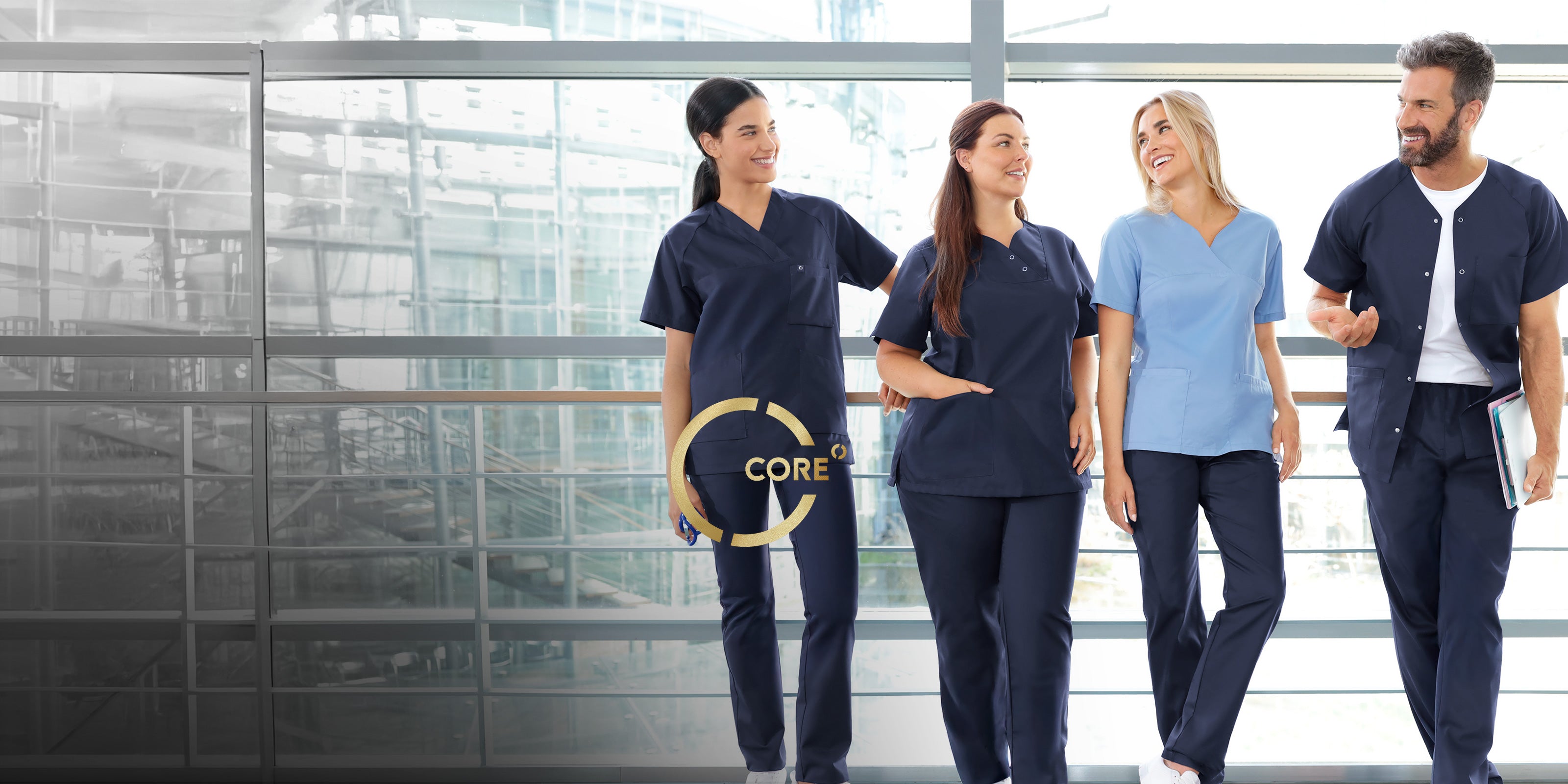 Quatre professionnels de santé portant des tenues médicales CORE bleu marine et bleu clair dans un établissement de santé moderne.