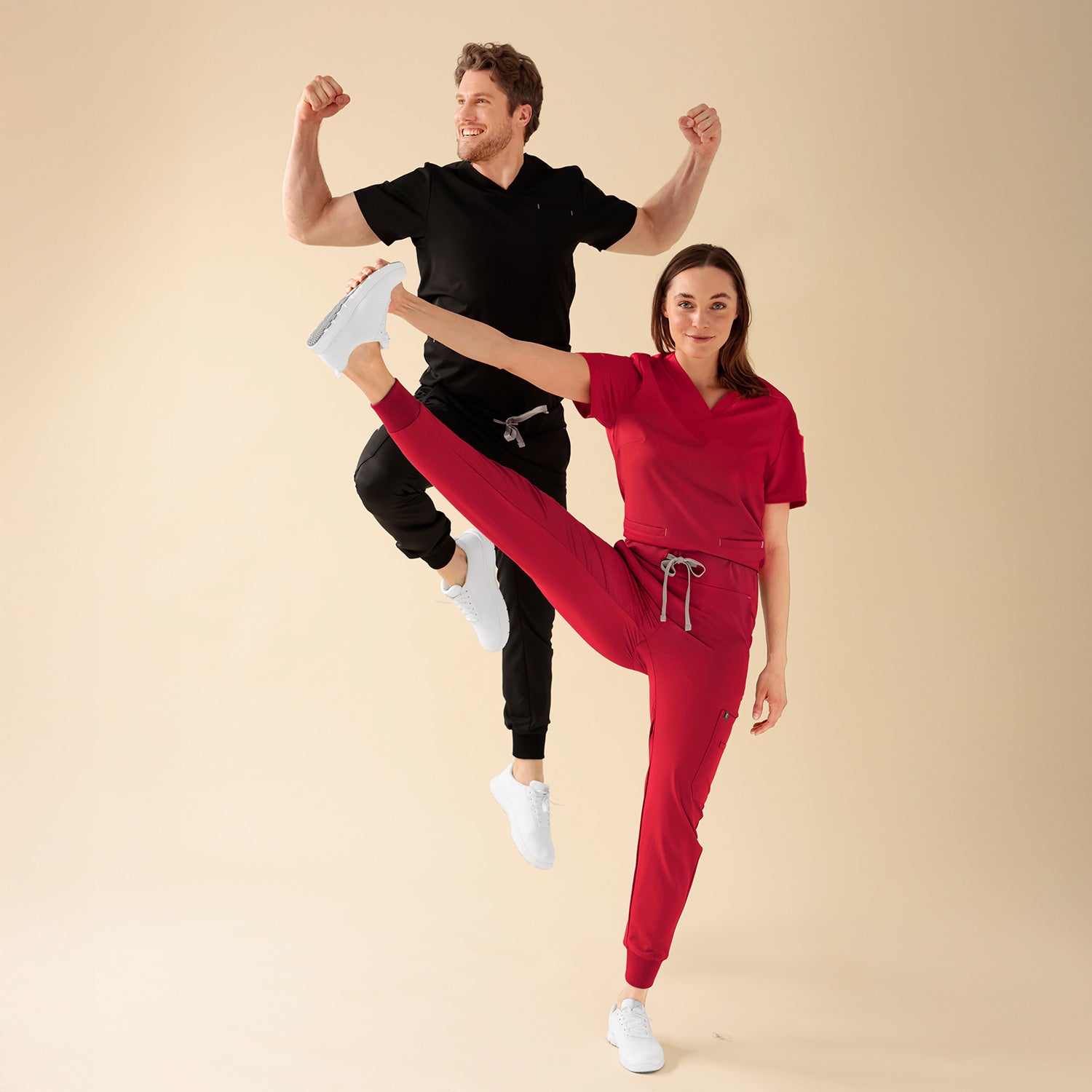 KAERE Multifunktions-Outfits, energiegeladene Team-Aufnahme mit springendem Herren-Model und Damen-Model mit Spagat-Pose. 